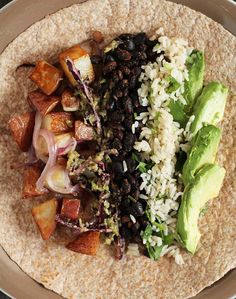 a tortilla with black beans, lettuce and avocado on top