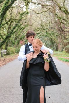 a man in a tuxedo carrying a woman in a black dress down a road