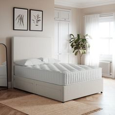 a white bed sitting in a bedroom next to a window