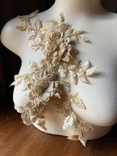 a white mannequin with flowers on it's back and gold trimmings