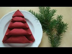 a white plate topped with red napkins next to a pine tree decoration on a table