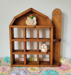 a wooden doll house with an owl figurine sitting on top of the shelf