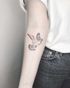 a woman's arm with a small bird tattoo on the left side of her arm