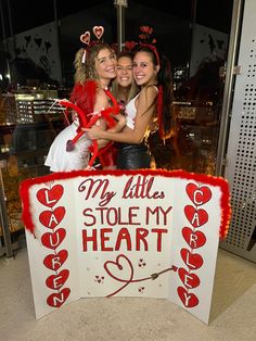 two girls are posing in front of a sign that says my little stole my heart