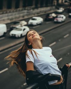 a woman standing on the side of a road next to a traffic filled city street