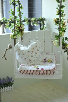 an image of a white swing bed with flowers on the top and bottom, in front of a window