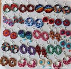 there are many pairs of earrings on the white board with different colors and designs hanging from them