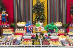 a table filled with cake, cupcakes and decorations for a avengers birthday party