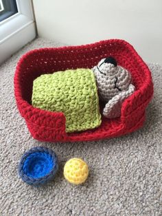 a crocheted dog bed and toy balls on the floor