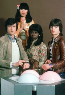 four people standing in front of a table with balloons on it and one person holding a balloon