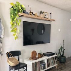 a flat screen tv mounted to the side of a wall next to a wooden shelf