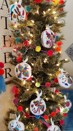 a decorated christmas tree with colorful ornaments on it's branches and decorations hanging from the top