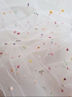 white fabric with colorful flowers on it and sheer tulle over the top, as seen from above