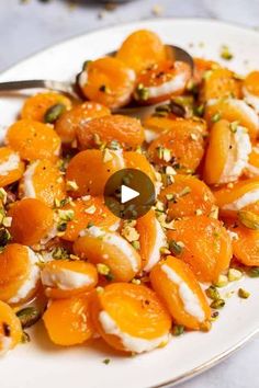 a white plate topped with sliced oranges and feta cheese covered in olives