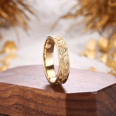 a gold wedding ring sitting on top of a wooden stand