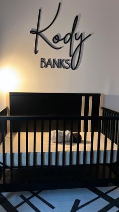 a baby's room with a black crib and name sign on the wall