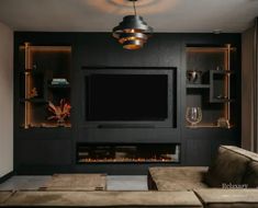 a living room with a couch, television and shelves on the wall in front of it