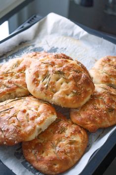 freshly baked bread with rosemary sprigs on top sitting on a baking sheet, ready to be eaten