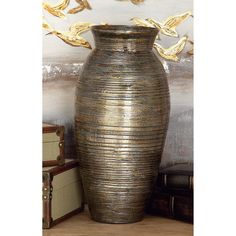 a large vase sitting on top of a wooden table next to boxes and suitcases