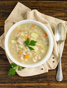 a bowl of chicken and dumpling soup on top of a napkin with a spoon