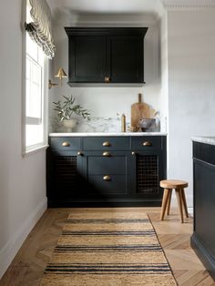 a kitchen with black cabinets and white counter tops, gold pulls on the cabinet doors