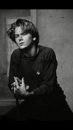 black and white photograph of a young man sitting on a chair with his hands crossed