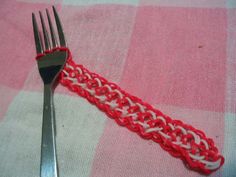 a fork with a red and white crocheted handle sits on a pink checkered tablecloth