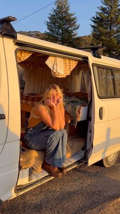 a woman sitting in the back of a van talking on a cell phone