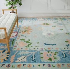 a blue rug with flowers on it and a bench in the corner next to it