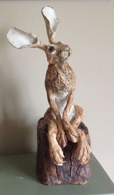 a statue of a rabbit sitting on top of a wooden stump