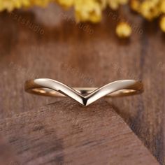 a gold wedding band on top of a wooden table with yellow flowers in the background