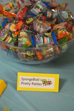 a bowl filled with lots of candy sitting on top of a blue tablecloth covered table