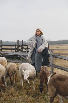 a woman standing in front of a herd of sheep