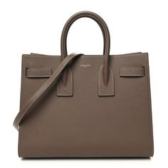 This is an authentic SAINT LAURENT Grained Calfskin Topstitch Small Classic Sac De Jour in Taupe. This elegant tote is crafted of grained calfskin leather in dark beige. The bag features rolled leather top handles, an optional leather shoulder strap, and short side straps that can be undone to increase the width of the bag. The top opens to a matching leather interior with a central removable zipper pouch. Tan Purse, Dark Beige, Leather Interior, Leather Top, Zipper Pouch, Calf Skin, Saint Laurent, Shoulder Strap, Handles