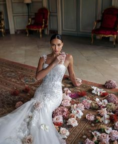 a woman in a wedding dress sitting on the floor with flowers all over her body