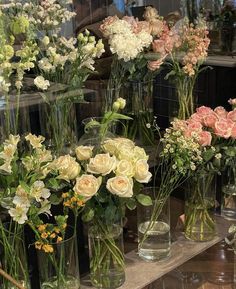 many vases filled with different types of flowers sitting on a shelf next to each other