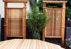 a wooden table sitting in the middle of a yard next to a fence and bushes