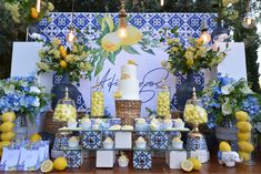 a table topped with a cake and lots of lemons next to blue and white decorations