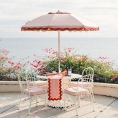 an umbrella is set up on the patio table with four chairs and a bottle of wine