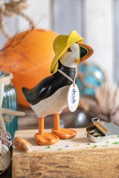 a toy duck wearing a hat and holding a name tag on it's neck