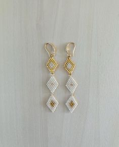 Stunning white and gold diamond garland bead earrings! 3 beaded diamond shapes create a featherweight garland. Extremely light weight design for daily wear! Each bead is hand sown row after row. Glass beads reveal a beautiful shine as they catch the light. Could be worn daily or on a special occasion.  Make a statement with these handmade bead earrings with a modern and bold design.  Minimalist with a pop of color to brighten up any outfit or occasion. 14K plated gold earring components. Unique Gold Nickel-free Beaded Earrings, Geometric Beaded Gold Earrings, Gold Beaded Dangle Clip-on Earrings, 14k Gold-filled White Linear Long Drop Earrings, 14k Gold-filled White Dangle Earrings, Gold Garland, Design Minimalist, Gold Earring, Handmade Beads