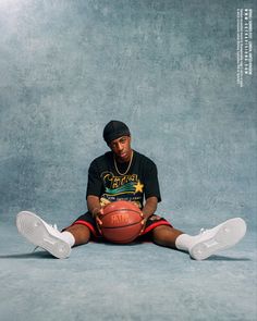 a man sitting on the floor with a basketball in his hand and wearing white shoes