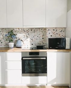 a kitchen with white cupboards and a black stove top oven next to a microwave