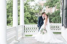 a bride and groom standing on the porch of their wedding venue in front of an elegant white gazebo