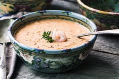 a bowl of soup with shrimp and parsley on the side, ready to be eaten