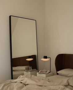 a bedroom with a large mirror on the wall and a bed in front of it