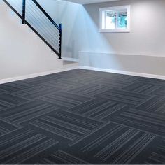 an empty room with black carpet and stairs