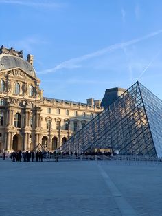 a large building with a pyramid in front of it and people walking around the area