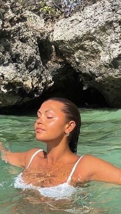 a woman is swimming in the water near some rocks