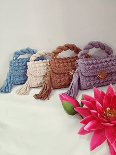 four crocheted bags with tassels and a pink flower on the side